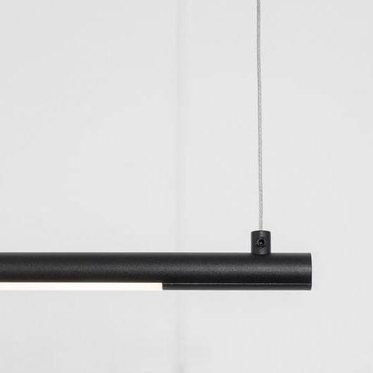 Czarna lampa wisząca Buga z jedną diodą LED o mocy 20W. Prosty, cylindryczny kształt z metaliczną teksturą. Zawieszona na cienkim, szarym przewodzie, na jednolitym, jasnym tle. Idealna do nowoczesnych wnętrz.