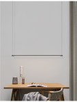 Lampa wisząca Buga w kolorze czarnym, z jedną diodą LED o mocy 20W. Produkt zawieszony w poziomie, z minimalistycznym designem, nad drewnianym biurkiem w jasnym otoczeniu. Kabel w kolorze czarnym, prosta forma bez dodatkowych zdobień.