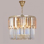 Lampa wisząca Camille z ośmioma miejscami na żarówki E14, z złotą metalową podstawą i ozdobnym kloszem z przezroczystych kryształów. Ujęcie z boku, wisząca, prezentująca elegancki design i efektowne odbicia światła.