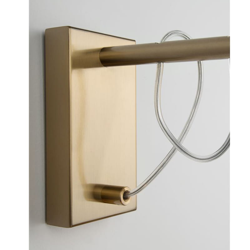 Kinkiet Ahigal w kolorze złotym, montowany na ścianie. Wykonany z metalu, z prostokątną podstawą i okrągłym uchwytem na żarówkę E14. Widoczny przezroczysty kabel. Ujęcie z boku, ukazujące szczegóły konstrukcji.