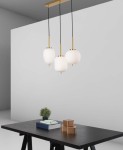 Lampa wisząca Pilar 3xE14 w złotym wykończeniu, z trzema białymi kloszami o kształcie elipsy, zawieszona na czarnych przewodach. Produkt umieszczony nad ciemnym stołem, w minimalistycznym wnętrzu z jednolitym tłem.