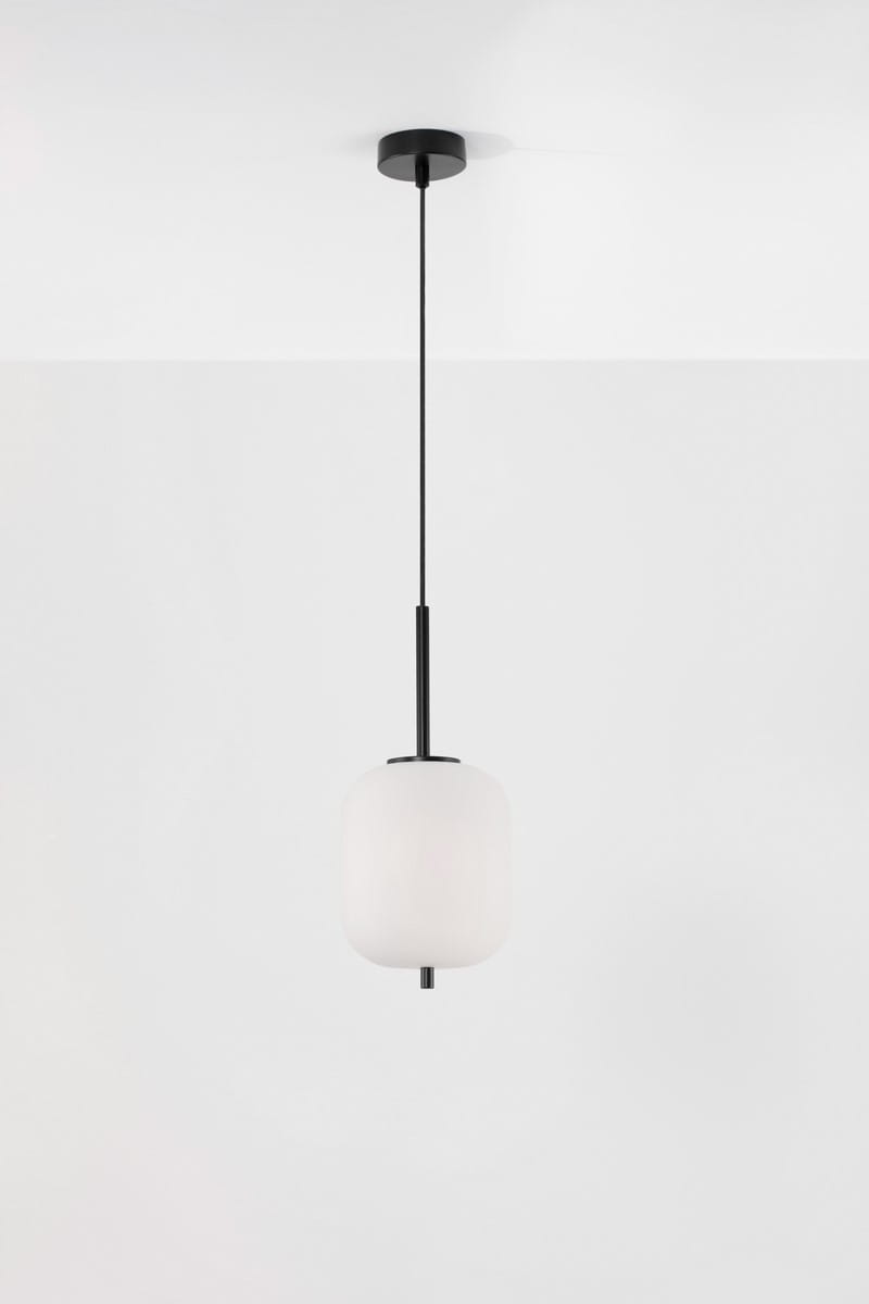 Lampa wisząca Marc L o wysokości 16,5 cm, czarna, z jednym gniazdem E14. Wyposażona w okrągły klosz z matowego szkła, zawieszona na cienkim czarnym kablu, w stylowym, minimalistycznym designie. Tło białe.
