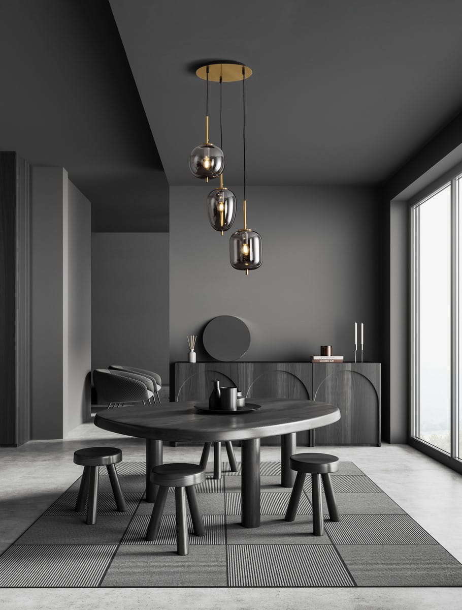 Lampa wisząca Pilar 3xE14 w kolorze złotym i czarnym, składająca się z trzech szklanych kloszy w kształcie kul. Produkt zawieszony na czarnych przewodach, umieszczony w nowoczesnym wnętrzu z ciemnymi meblami i jasnym dywanem.