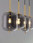 Lampa wisząca Pilar z czterema oprawami E14 w złotej metalowej konstrukcji. Szklane klosze w odcieniach szarości, wiszące na czarnych przewodach. Ujęcie z przodu, podkreślające elegancki design i źródła światła wewnątrz kloszy.