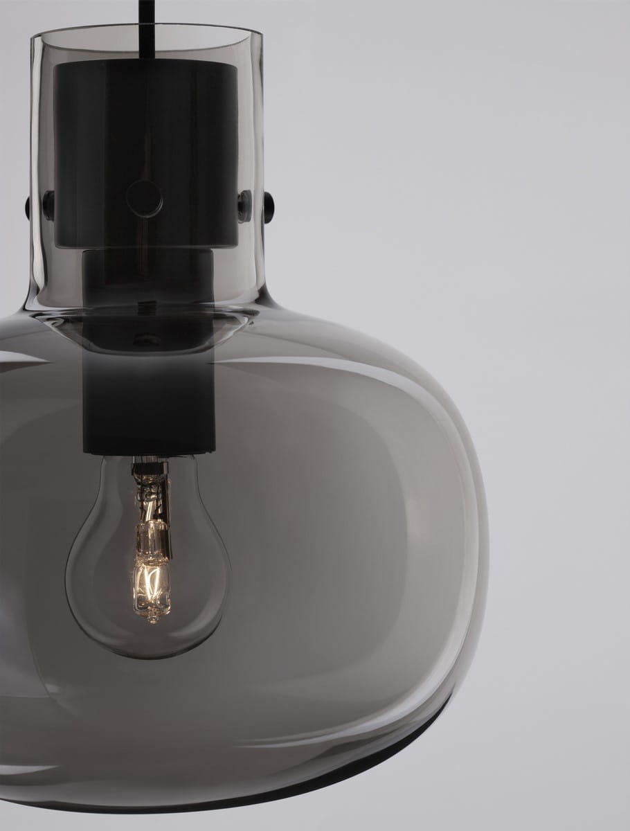 Lampa wisząca Padre z pojedynczym gniazdem E27, w czarnej oprawie. Szklany klosz w odcieniu dymnym, z widoczną żarówką. Ujęcie z góry, ukazujące detal mocowania i kształt klosza. Prosty, neutralny kontekst na jasnym tle.