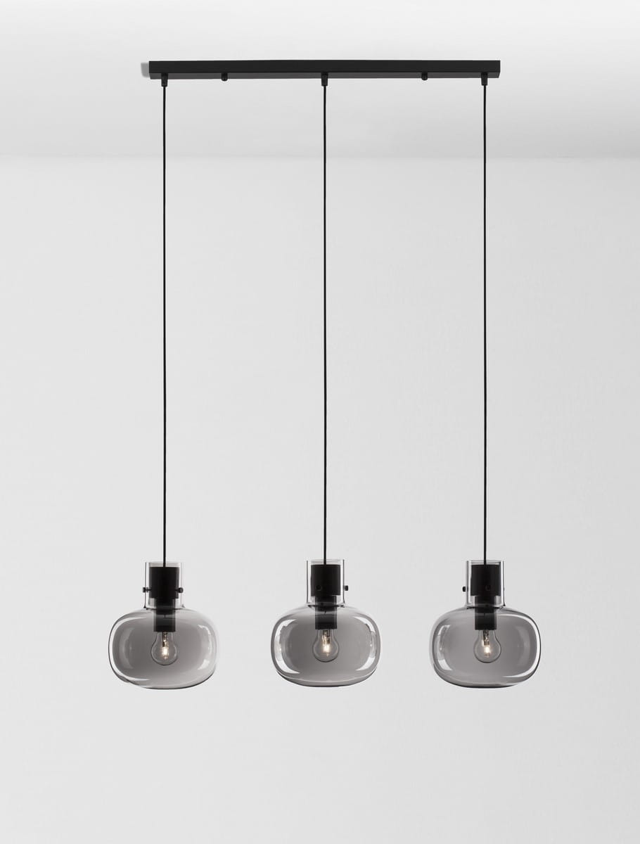 Czarna lampa wisząca Padre z trzema źródłami światła E27. Klosze w kształcie owalnym z przezroczystego szkła w odcieniu szaro-przezroczystym, zawieszone na czarnych linkach. Montaż na prostokątnej podstawie sufitowej.