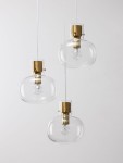 Lampa wisząca Padre z trzema kloszami, wykonana z przezroczystego szkła z elementami w kolorze złotym. Klosze mają owalny kształt, zawieszone na białych przewodach. Widoczne żarówki E27 wewnątrz kloszy. Tło proste, jasne.