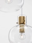 Lampa wisząca Padre z trzema źródłami światła E27, z metalowym złotym kloszem i przezroczystym szkłem. Ujęcie z bliska pokazuje detal mocowania oraz żarówki w dolnej części klosza. Proste tło podkreśla elegancki design lampy.