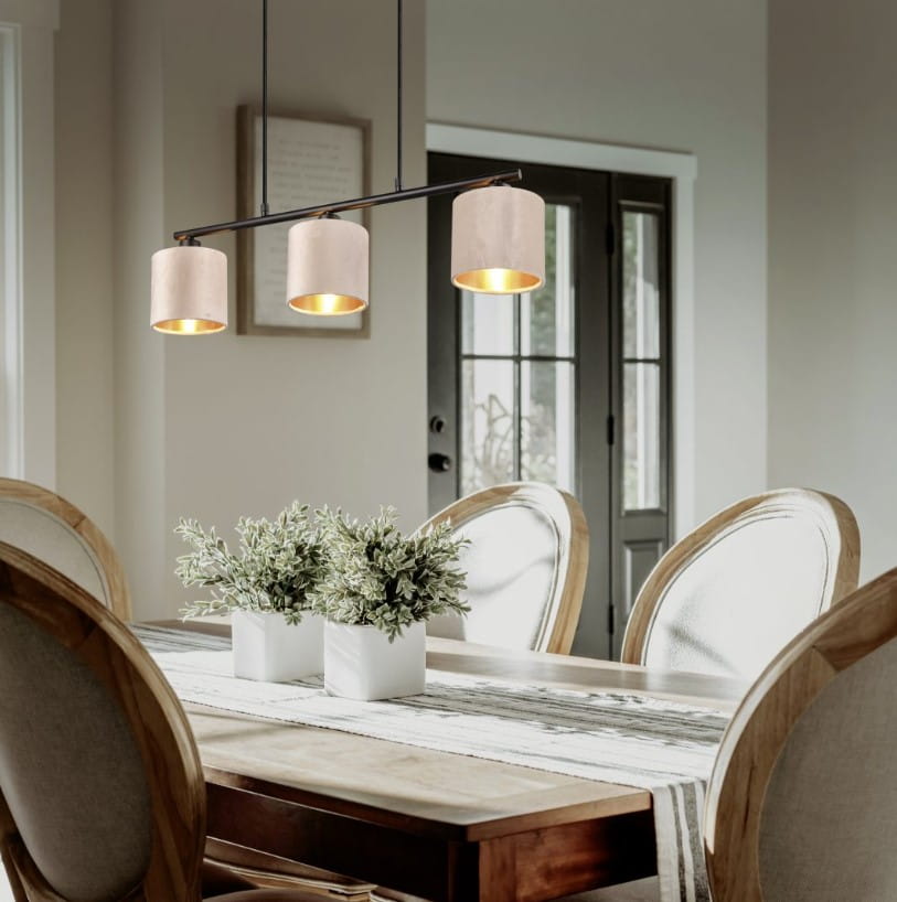 Lampa wisząca Julieta z trzema kloszami E14W w kolorze czarnym, zawieszona nad drewnianym stołem. Klosze mają jasne wnętrza, tworząc atmosferę przytulności w nowoczesnym wnętrzu. W tle widoczne krzesła oraz rośliny w doniczkach.