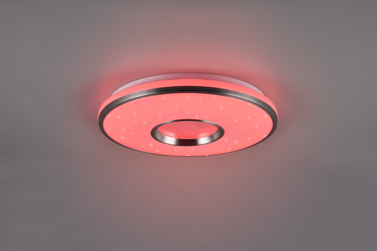 Plafon Realta z pilotem w kolorze czerwonym, wykonany z aluminium, z okrągłym kształtem i centralnym otworem. Emituje światło LED 24W, z dekoracyjnymi gwiazdami na powierzchni. Zawieszony na jasnym tle, widoczny z frontalnego kąta.