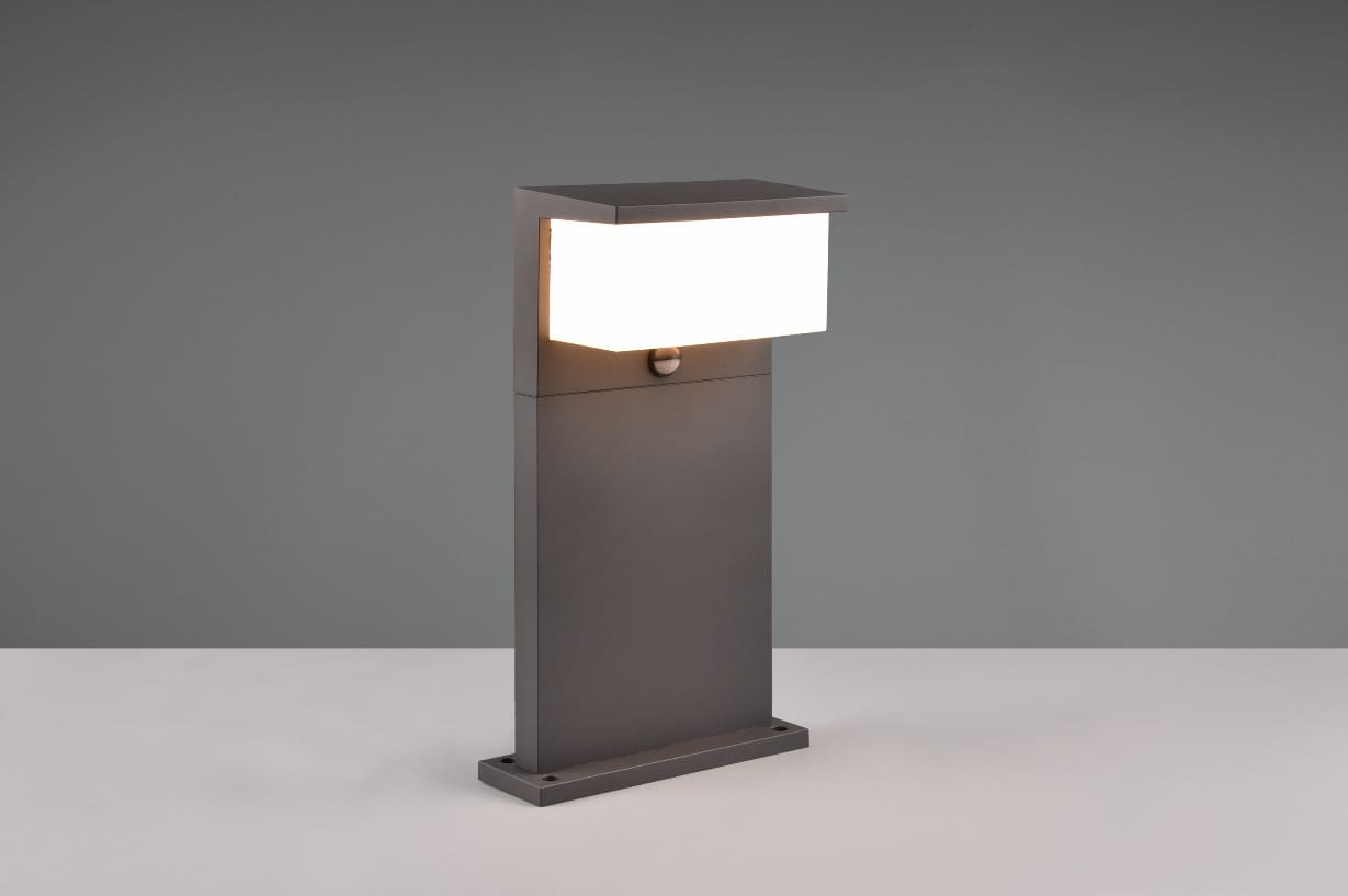 Stojąca lampa zewnętrzna Nestos H45 w kolorze antracytowym, z prostokątną górą z białym kloszem LED. Produkt z czujnikiem ruchu, umieszczony na płaskiej podstawie. Prosty, nowoczesny design, idealna do ogrodu lub na taras.