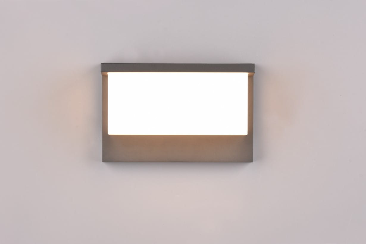 Kinkiet zewnętrzny Nestos LED w kolorze antracytowym. Prosty, kwadratowy kształt z białą, matową osłoną, emitującą światło. Ujęcie frontalne, produkt zamontowany na gładkiej, jasnej powierzchni. Idealny do oświetlenia elewacji budynków.
