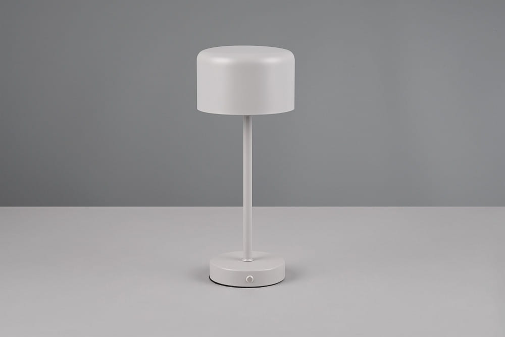 Lampa stołowa Jeff w kolorze szarym z metalowym stelażem, o okrągłej podstawie i cylindrycznym kloszu. Ujęcie frontalne, stojąca na jednolitym tle. Widoczny przycisk włącznika na podstawie. Wbudowane źródło światła LED o mocy 1,5W.