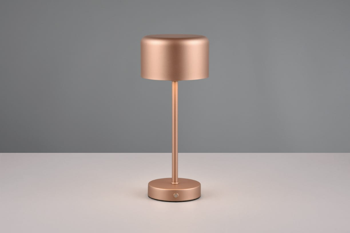 Lampa stołowa Jeff w kolorze kawowym, z metalową podstawą i cylindrycznym kloszem. Ujęcie frontalne, lampa stoi na białym blacie. Widoczny przycisk na podstawie. Wysoka, minimalistyczna konstrukcja z 1xLED/1,5W.