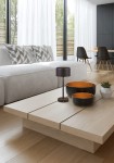Czarna lampa stołowa Jeff z jedną diodą LED o mocy 1,5W, umieszczona na drewnianym stole. Lampa ma prosty, cylindryczny kształt, obok niej znajdują się dwa czarne talerze i roślina w doniczce. Tło stanowi nowoczesne wnętrze z jasnymi zasłonami.