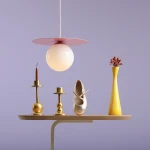 Lampa wisząca Loop Baby Pink S z okrągłym kloszem w kolorze białym i różową podstawą, zawieszona nad drewnianym blatem. W tle złote świeczniki, złota baletka i żółty wazon z kwiatami, na fioletowym tle.