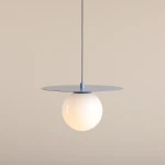 Lampa wisząca Loop w kolorze błękitnym, z okrągłą, białą kulą na metalowej podstawie. Zawieszona na cienkim przewodzie, z płaskim, okrągłym elemencie u góry. Prosta forma, idealna do nowoczesnych wnętrz.