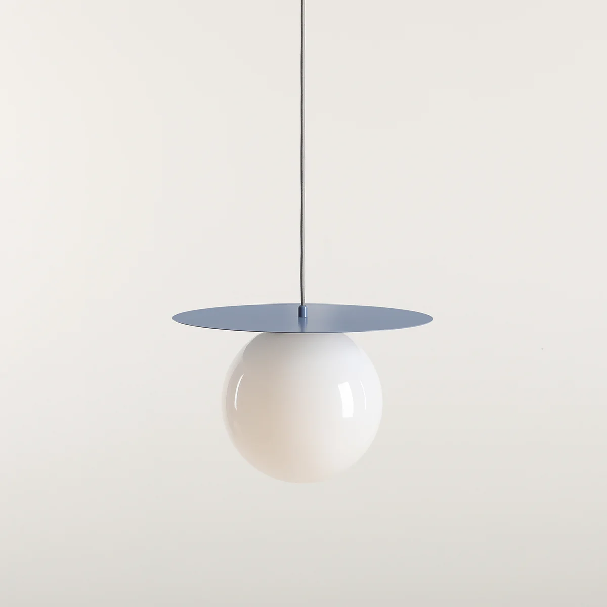 Lampa wisząca Loop w kolorze błękitnym z metalowym, okrągłym kloszem oraz szklaną, białą kulą. Zawieszona na cienkim przewodzie, prezentuje nowoczesny design. Idealna do oświetlenia wnętrz.