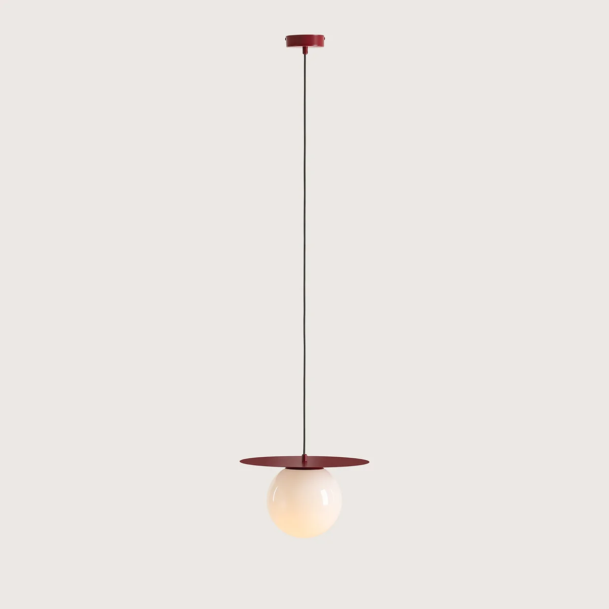 Czerwona lampa wisząca Loop Red Wine M z jedną oprawą E27. Kula ze szkła w kolorze jasnym zawieszona na cienkim przewodzie, z metalowym, okrągłym elementem w górnej części. Prosty, minimalistyczny design.