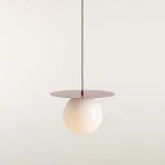 Lampa wisząca Loop Red Wine L z okrągłym, białym kloszem i czerwonym, płaskim daszkiem. Produkt zawieszony na czarnym przewodzie, prezentujący nowoczesny design. Tło jasne, jednolite, podkreślające elegancję lampy.