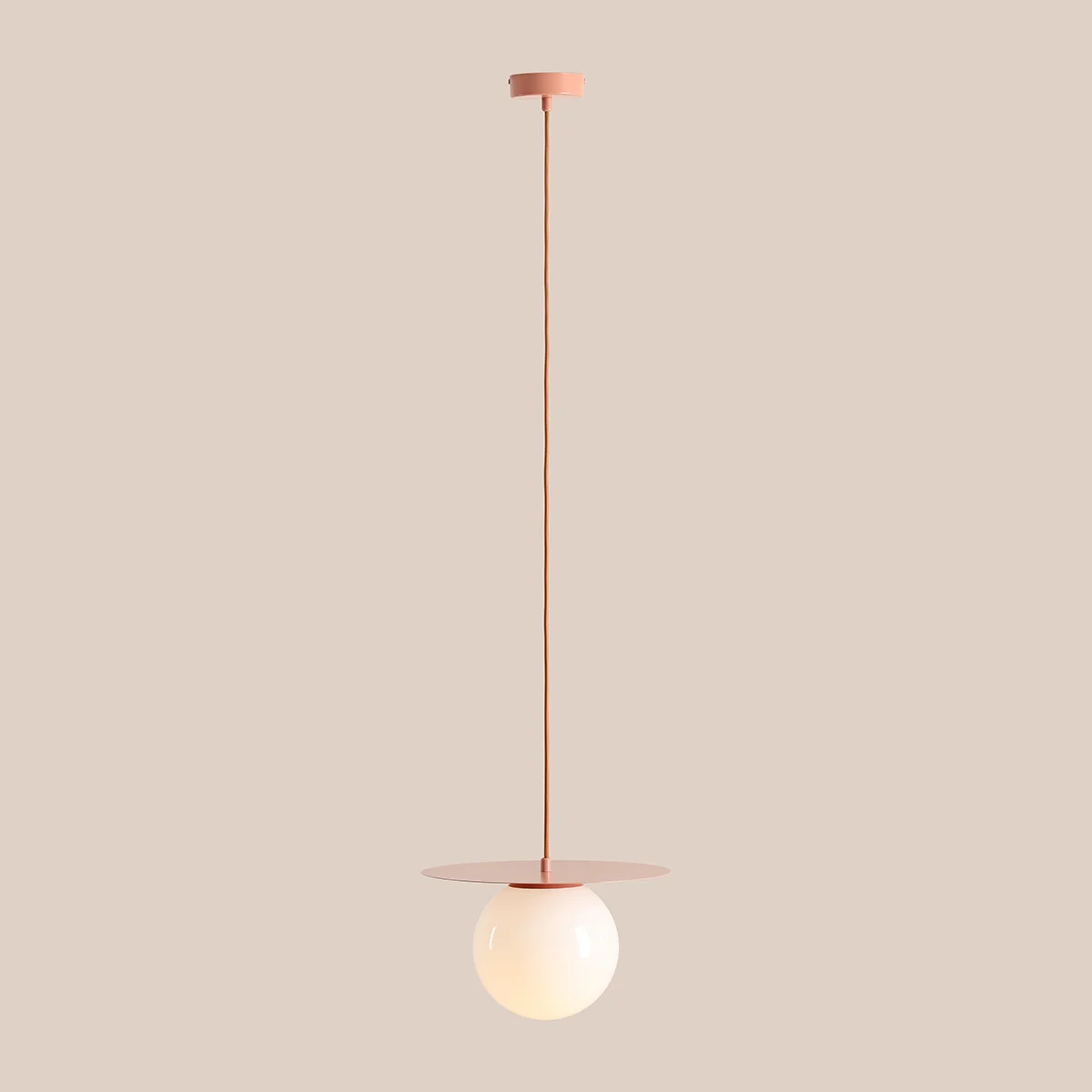 Lampa wisząca Loop Coral M z oprawą w kolorze koralowym, z długim przewodem. Posiada szklany klosz w kształcie kuli, umieszczony na metalowej podstawie w formie okrągłej płytki. Produkt zawiera miejsce na żarówkę E27.