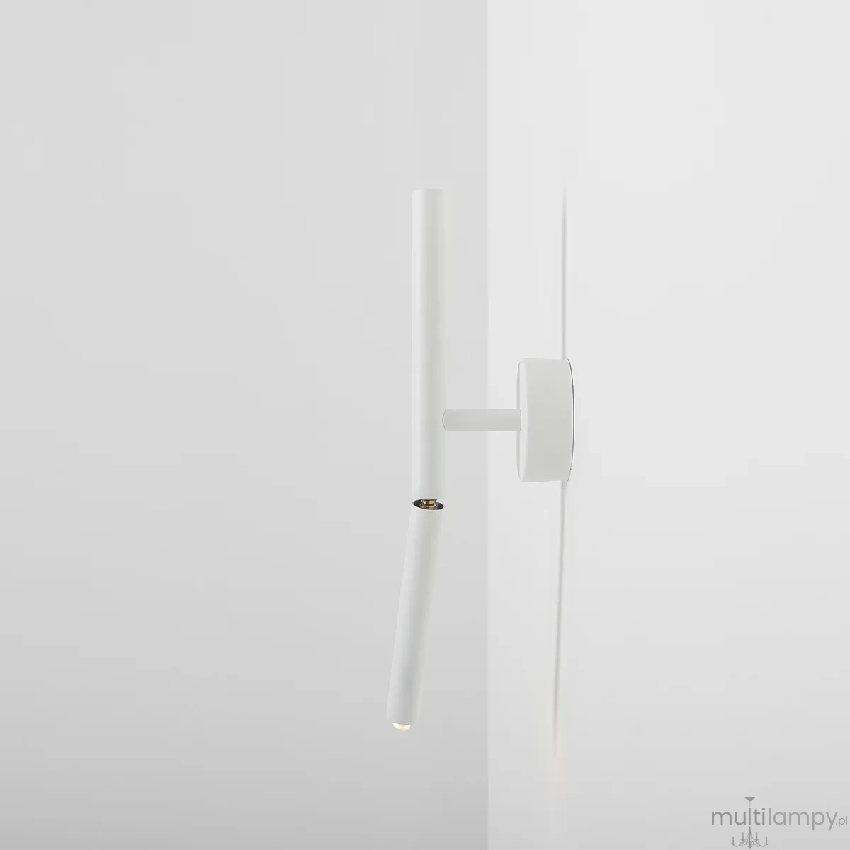Kinkiet Stick 1xG9 w kolorze białym, zamontowany na ścianie. Posiada prostą, cylindryczną formę z widocznym źródłem światła na końcu. Obok, okrągła podstawa w tym samym kolorze. Tło jasne, minimalistyczne.