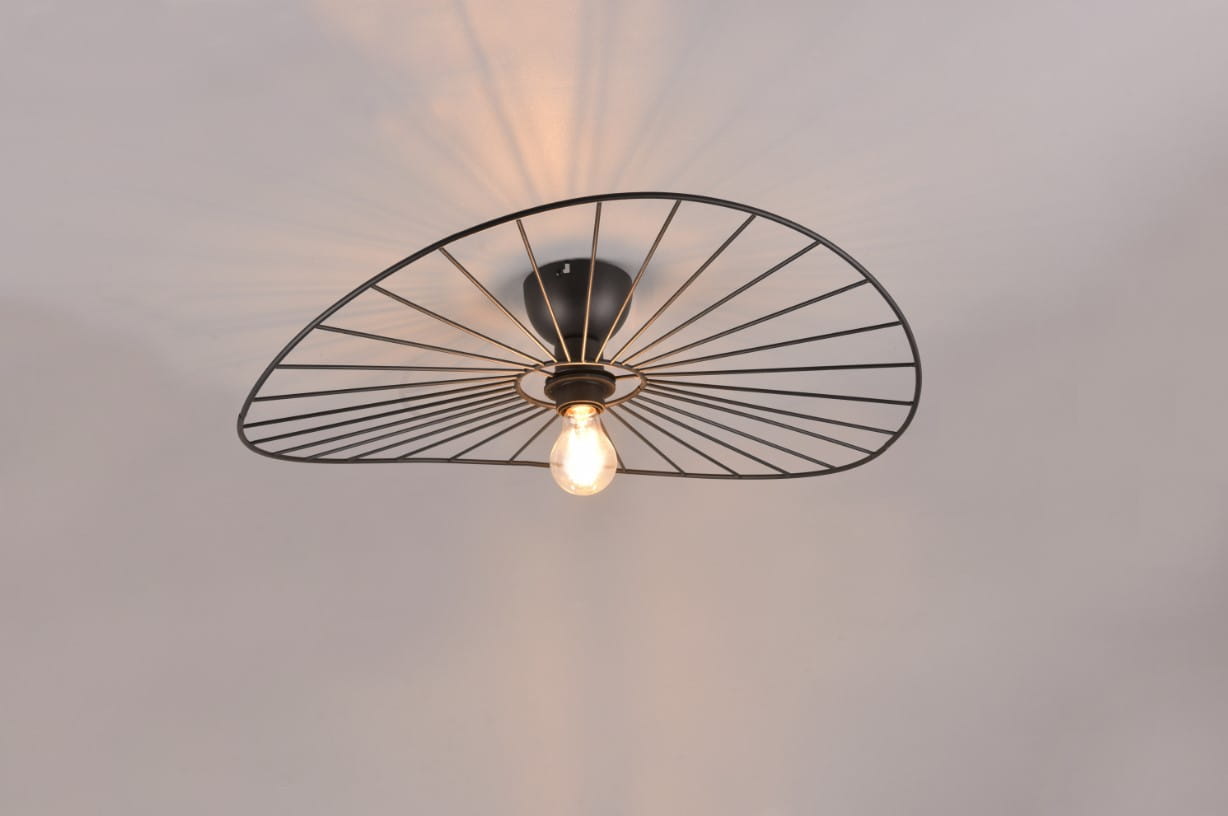 Czarna lampa sufitowa Chapeau z jednym gniazdem E27, z metalową, siatkową osłoną w kształcie elipsy, montowana na suficie. Widoczna żarówka w centralnej części, emitująca ciepłe światło. Tło jasne, podkreślające detale lampy.