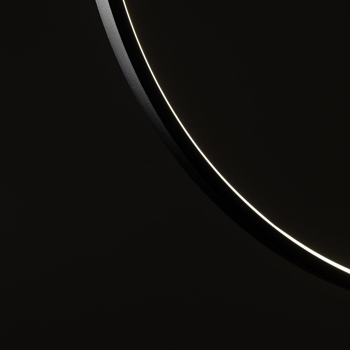 Czarna lampa wisząca Circolo D45 z jednym źródłem LED o mocy 18W i barwie światła 3000K. Ujęcie detalu lampy, z widocznym okrągłym kształtem oraz subtelnym, podświetlonym brzegiem. Tło ciemne, co podkreśla elegancki design.