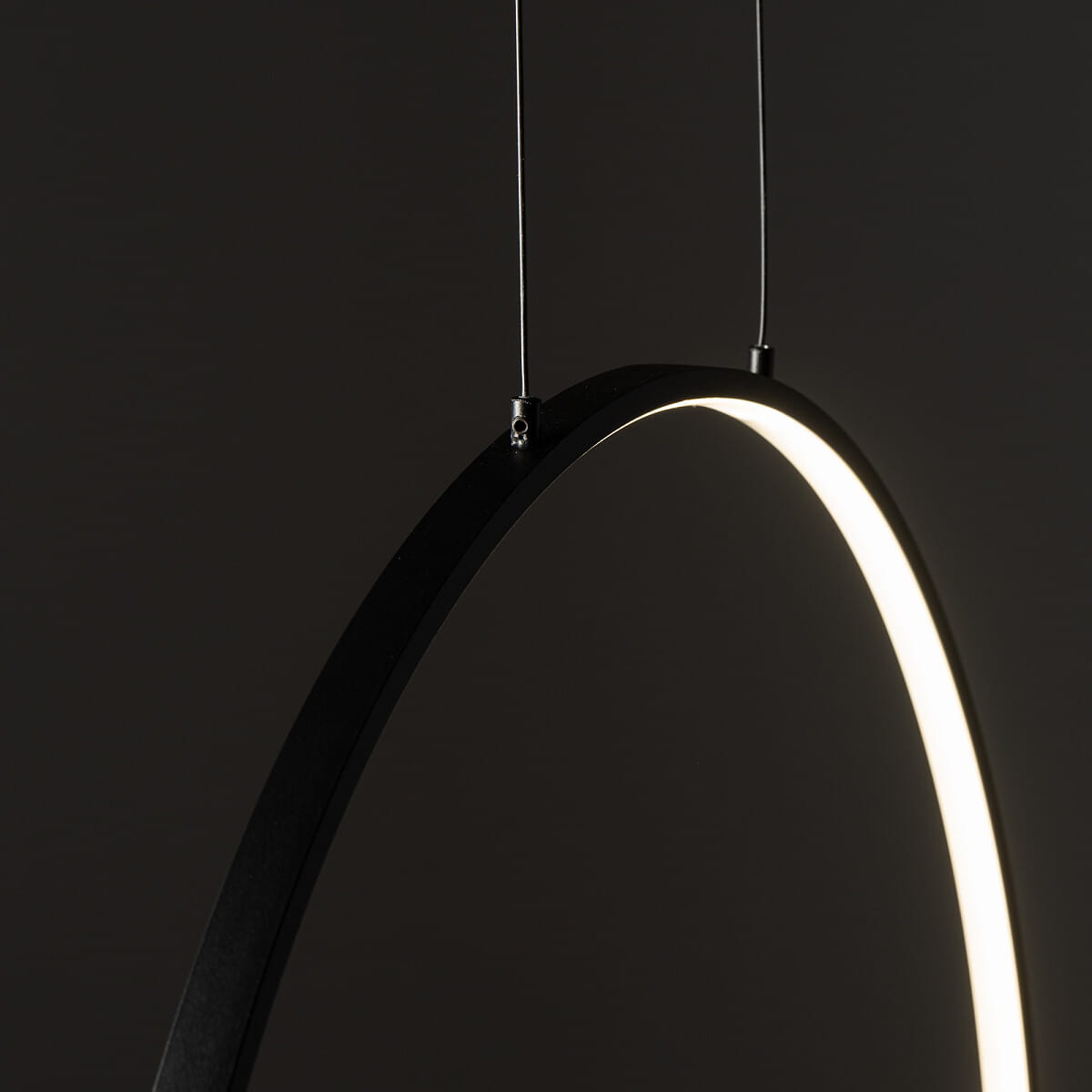 Lampa wisząca Circolo D60 w kolorze czarnym, z LED o mocy 21W i temperaturze barwowej 3000K. Ujęcie z boku, ukazujące smukły, okrągły kształt oraz emitowane światło z wewnętrznej krawędzi. Zawieszona na cienkich linkach.