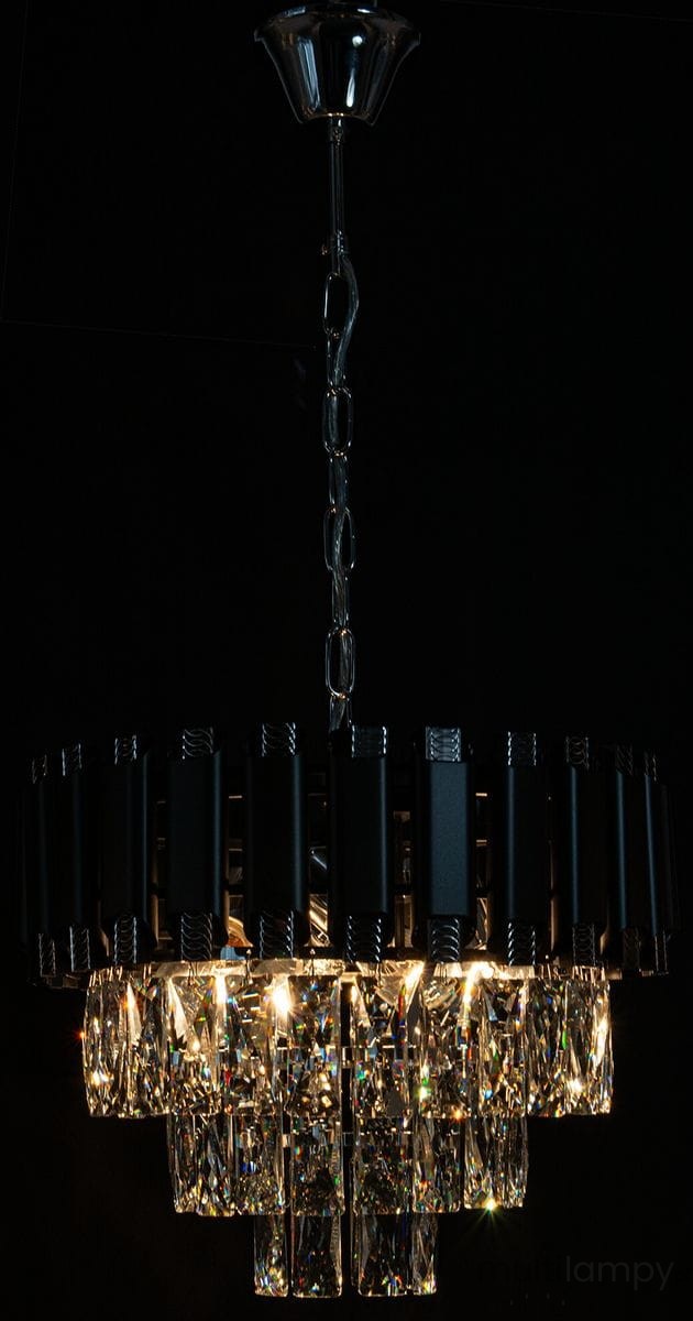 Lampa wisząca Bilbao z czarnym abażurem i chromowanymi detalami, wyposażona w cztery oprawy E27. W dolnej części znajdują się przezroczyste, kryształowe elementy, które odbijają światło. Ujęcie z dołu, wisząca konstrukcja.