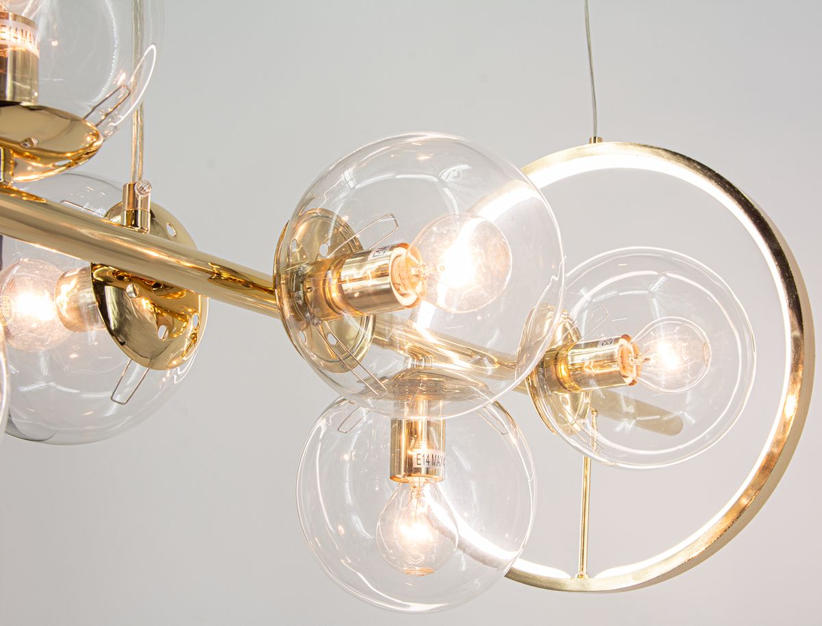 Lampa wisząca Galaxy z siedmioma oprawami E14 i jedną LED. Złota konstrukcja z przezroczystymi kloszami w kształcie kul, umieszczona na metalowej ramie z okrągłym detalem. Ujęcie z boku, eksponujące źródła światła i elegancki design.