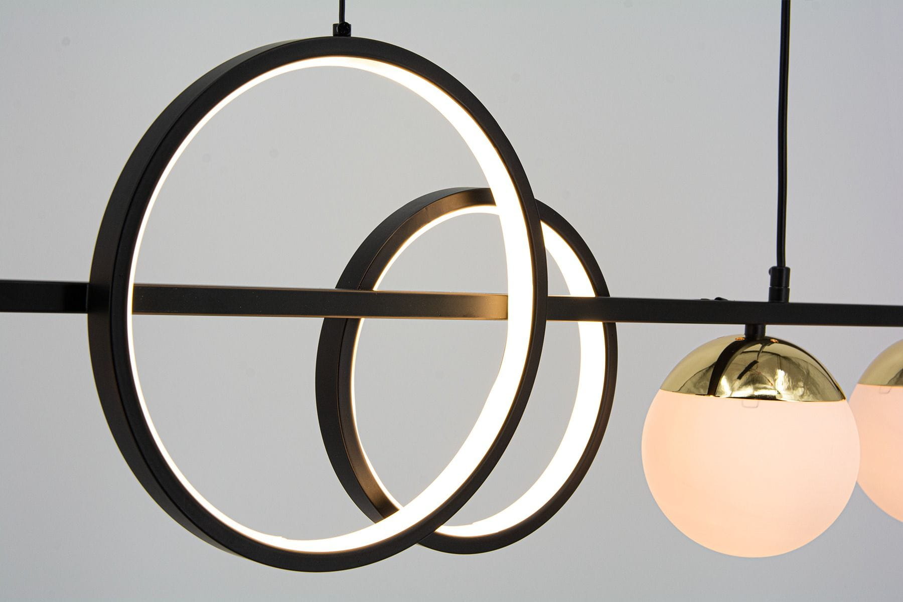 Lampa wisząca Malmo w kolorze czarnym i złotym z trzema okrągłymi elementami LED oraz dwiema kulistymi oprawami z mlecznego szkła. Ujęcie z góry, z widocznymi detalami konstrukcyjnymi i oświetleniem.