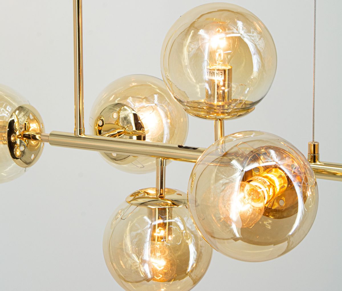 Lampa wisząca Paco 6xE14 w kolorze złotym, z sześcioma przezroczystymi kulistymi kloszami. Ujęcie z góry pokazuje elegancką strukturę i wykończenie. Klosze eksponują źródła światła, tworząc efektowne oświetlenie.