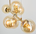 Lampa wisząca Paco z sześcioma kulistymi kloszami z przezroczystego szkła, osadzona na złotej konstrukcji. Widoczne źródła światła E14, elegancki design, zawieszona w górnej części zdjęcia na cienkim przewodzie. Tło jasne, minimalistyczne.