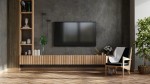 Czarny kinkiet Motive 120 z jedną żarówką LED o mocy 16W i temperaturze barwowej 4000K. Zawieszony na ścianie, minimalistyczny design, idealny do nowoczesnych wnętrz. W tle telewizor i drewniana szafka.