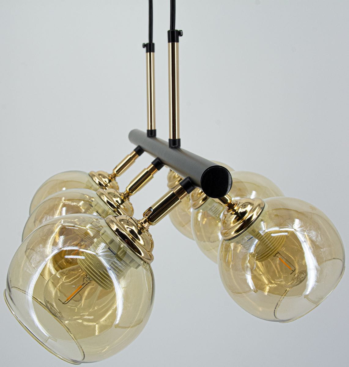 Lampa wisząca Piran z sześcioma kloszami E27 w kolorze czarnym i złotym. Klosze mają okrągły kształt, transparentne szkło, a podstawa jest matowa. Produkt zawieszony na dwóch smukłych linkach, na jasnym tle.
