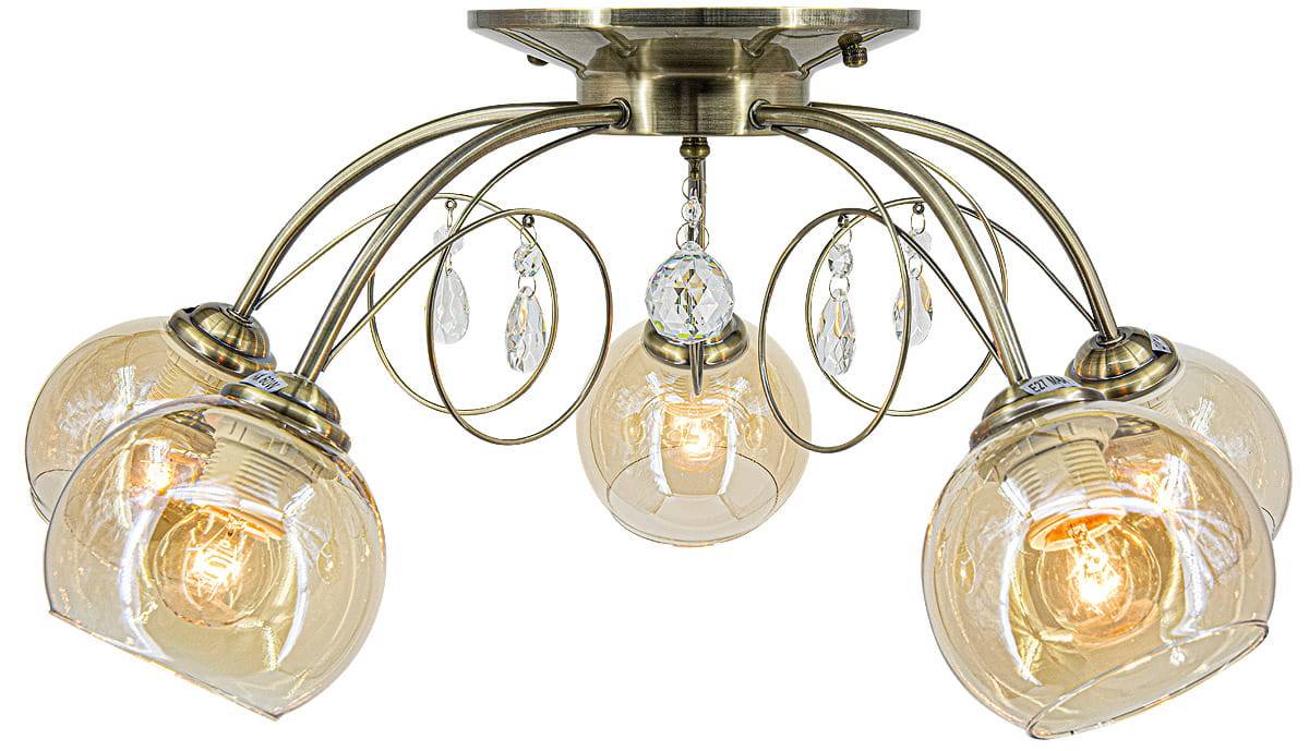 Lampa sufitowa Carmen 5-punktowa w kolorze mosiądzu. Posiada pięć szklanych kloszy w kształcie kul, ozdobionych kryształkami. Ujęcie z dołu, ukazujące detale konstrukcji oraz żarówki wewnątrz kloszy.