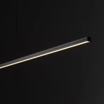 Czarna lampa wisząca Bar L120, prostokątna, z jedną diodą LED o mocy 21W i barwie światła 3000K. Zawieszona pod kątem z górnym oświetleniem, z widoczną cienką, elegancką oprawą. Tło ciemne, podkreślające minimalistyczny design.