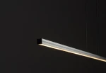 Lampa wisząca Bar L120, czarna, o prostokątnym kształcie, z wbudowanym źródłem LED 21W, 3000K. Ujęcie z boku, pokazujące delikatne światło emitowane z dolnej krawędzi, zawieszona na cienkich żyłkach, na ciemnym tle.