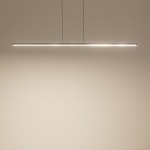 Lampa wisząca Bar L150 w kolorze czarnym, długości 150 cm, z jedną diodą LED o mocy 24W i temperaturze barwowej 3000K. Zawieszona równolegle do ściany, emitująca ciepłe światło. Prosty, minimalistyczny design na jasnym tle.