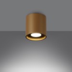 Złota lampa sufitowa Orbis z pojedynczym źródłem światła GU10, o cylindrycznym kształcie, montowana na suficie. Ujęcie frontalne, na szarym tle, ukazuje matową powierzchnię lampy oraz emitowane światło.