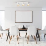 Biała lampa sufitowa typu spot z trzema oprawami GU10 w złotych detalach, zamontowana na suficie. W tle widoczna jasna aranżacja jadalni z drewnianym stołem i białymi krzesłami.