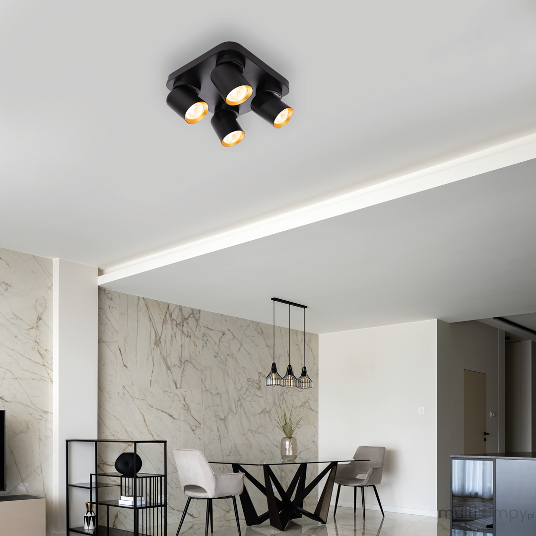 Lampa sufitowa Andy w kolorze czarnym i złotym, z czterema spotami GU10, zamontowana na suficie. Kąt ujęcia z góry, pokazujący nowoczesny design oraz otoczenie w eleganckim wnętrzu z marmurową ścianą i minimalistycznymi meblami.