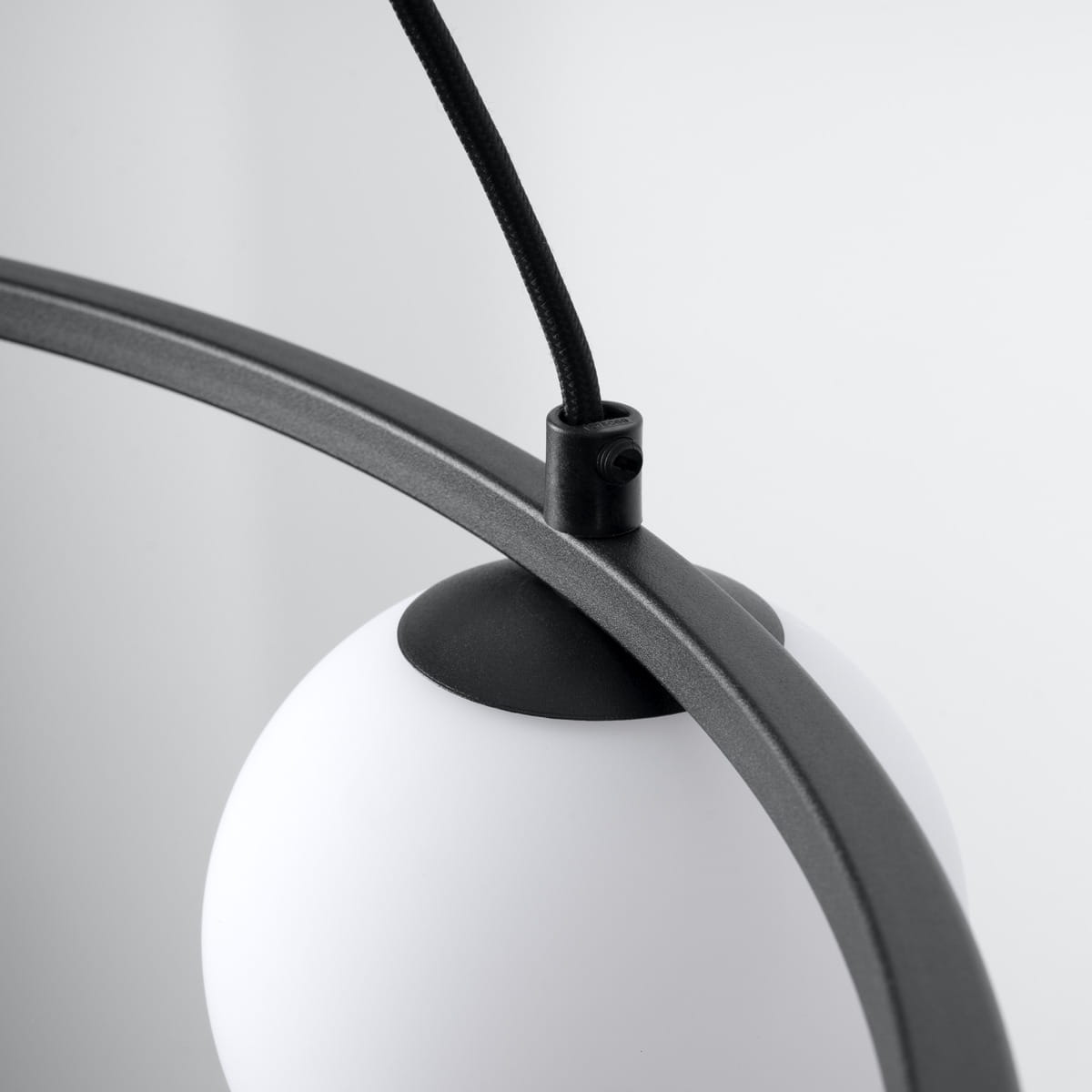 Lampa wisząca Yoli 3xG9 w kolorze czarnym, z metalowym stelażem i białym, okrągłym kloszem. Ujęcie z góry, ukazujące mocowanie i przewód. Prosta, nowoczesna forma, idealna do aranżacji wnętrz.