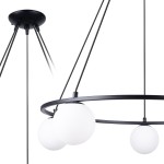 Lampa wisząca Yoli w kolorze czarnym z pięcioma źródłami światła G9. Okrągła metalowa konstrukcja z trzema białymi kulistymi kloszami. Ujęcie z boku, ukazujące detale zawieszenia i formę lampy.