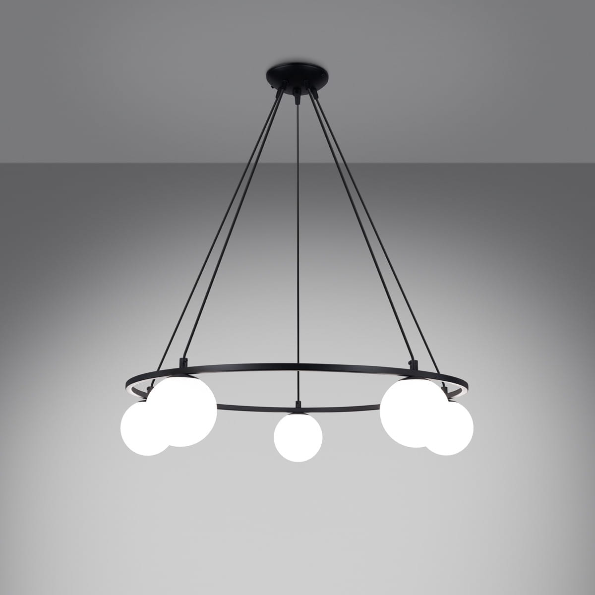 Lampa wisząca Yoli 5xG9 w kolorze czarnym, zawieszona na trzech linkach. Okrągła podstawa z pięcioma białymi kulistymi kloszami, zapewnia nowoczesny wygląd. Zdjęcie wykonane z dołu, ukazujące detal montażu i kształt lampy. Tło w odcieniach szarości.