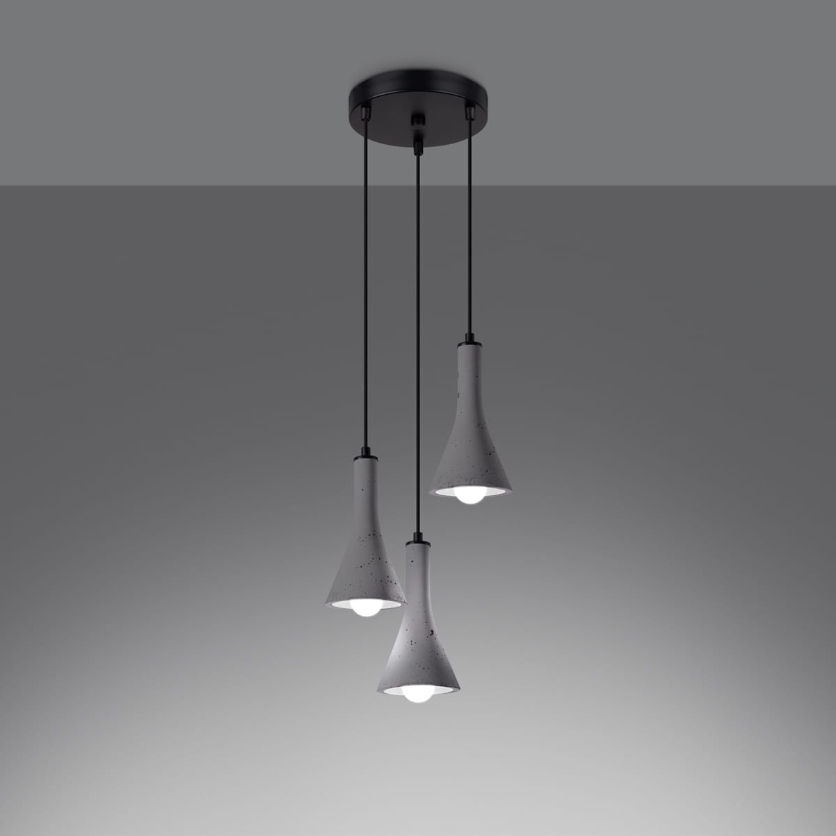Lampa wisząca Rea z trzema kloszami w kształcie dzwonu, wykonana z betonu w kolorze białym z szarymi akcentami. Klosze zawieszone na cienkich czarnych przewodach, montowane do okrągłej podstawy sufitowej w kolorze czarnym.