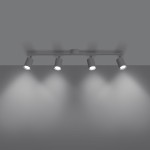 Lemmi lampa sufitowa (spot) z czterema oprawami GU10 w białym kolorze, zamontowana na metalowym stelażu. Ujęcie z dołu, z widocznym oświetleniem skierowanym na ścianę, na szarym tle.