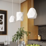 Lampa wisząca Mint 1xE27 w kolorze białym z geometrycznymi kształtami, zawieszona na długich linkach. W tle widoczna nowoczesna kuchnia z ciemnym blatem, zielonymi jabłkami i rośliną w szklanym wazonie.