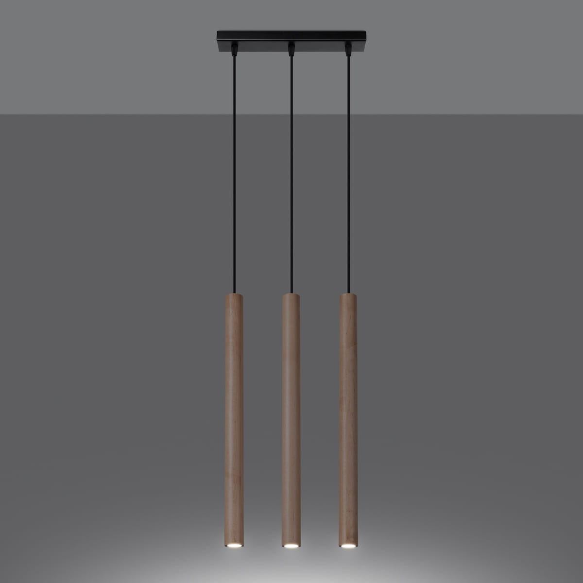 Lampa wisząca Pastelo z trzema tubami G9, w kolorze czarnym i drewnianym. Tubowe źródła światła zawieszone na cienkich czarnych linkach, z czarnym stropem. Minimalistyczny design, idealna do nowoczesnych wnętrz.
